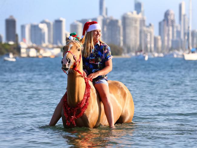 Shelby Wayt takes her palamino Aussie to the Spit to cool off for Christmas. Picture: Adam Head