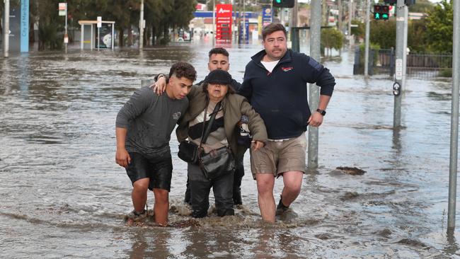 A man is helped by locals as he leaves his house on Raleigh Rd, Maribyrnong. Picture: David Crosling