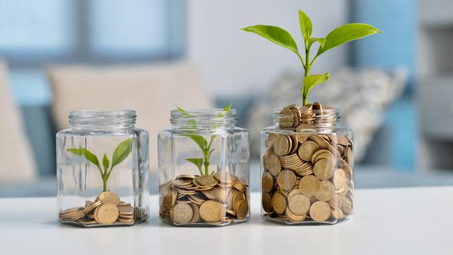 Green plant growing in glass jar with coins, superannuation generic