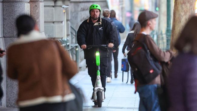 A person rides an e-scooter along the footpath on Flinders Street in Melbourne’s CBD Picture: Brendan Beckett