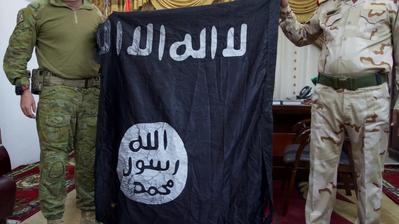 File: two soldiers hold a captured Islamic State flag.