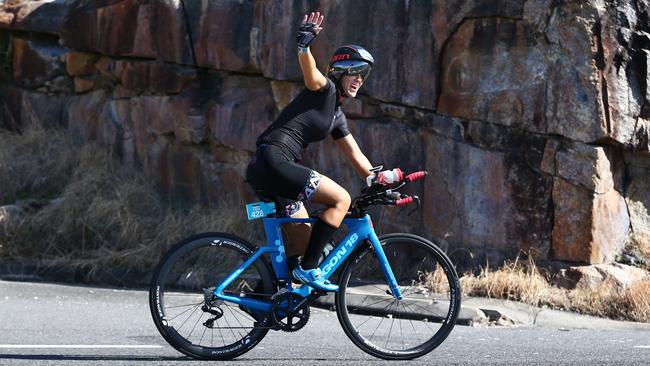 Tara Partridge waves as she rides over the Rex Lookout on the cycle leg of the Ironman Cairns. PICTURE: BRENDAN RADKE