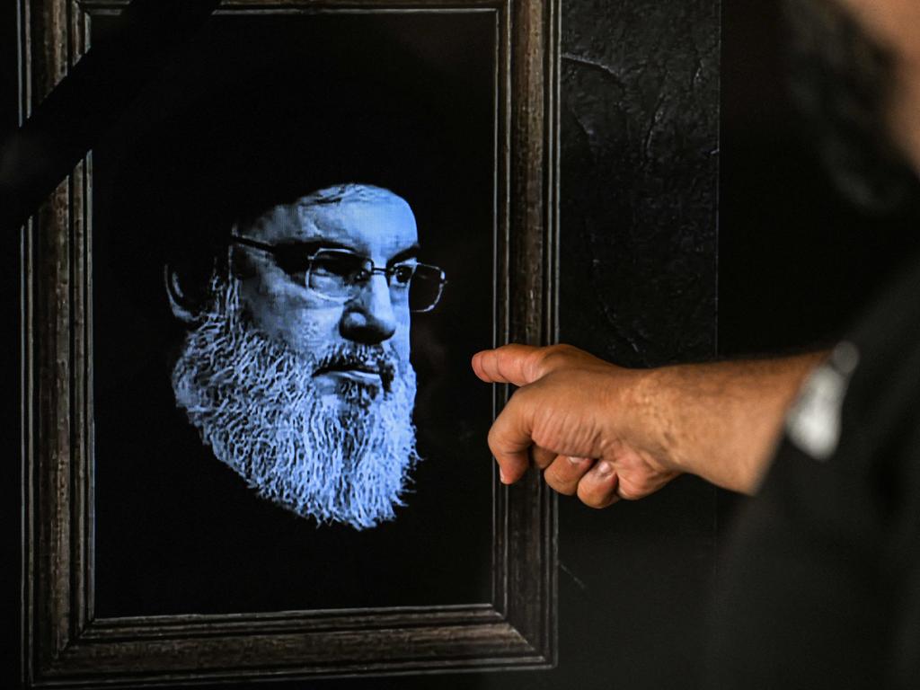 TOPSHOT - A man points to a television set displaying an image of the late leader of Hezbollah Hassan Nasrallah. Picture: AFP.