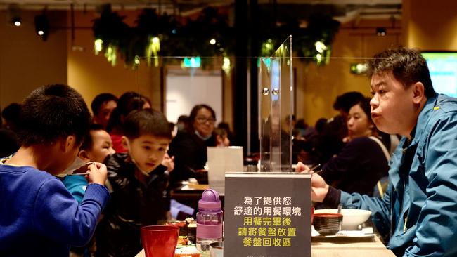 People divided by plastic partitions to reduce the spread of COVID-19 eat their food at Q Square in Xindian district, New Taipei City on April 3.