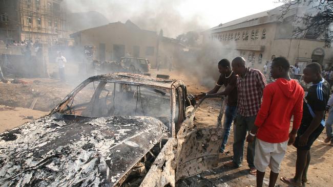 Men look at the burnt-out wreckage of a car following a bomb blast outside the Nigerian capital Abuja.