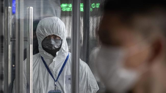 A Chinese health worker waits to check the temperature of travellers entering a train station during the Chinese New Year and Spring Festival on January 25, 2020 in Beijing, China. Picture: Kevin Frayer/Getty Images