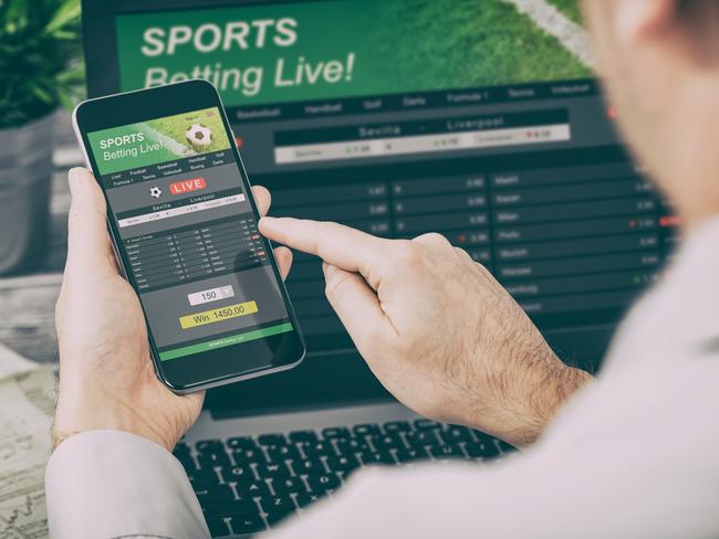 betting bet sport phone gamble laptop over shoulder soccer live home website concept - stock image