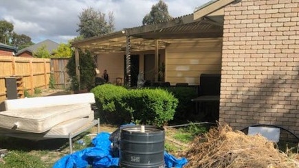 The backyard of this rooming house is full of rubbish and old furniture.