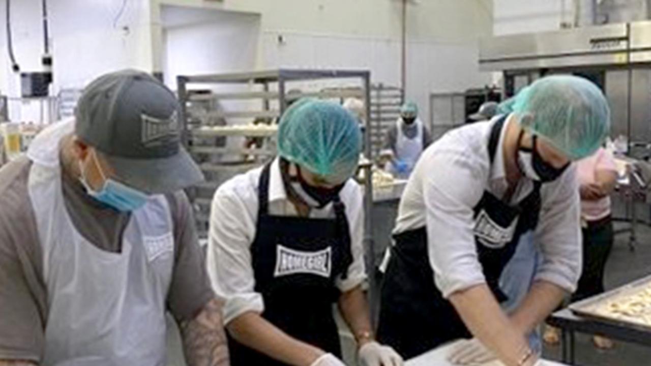 Prince Harry and Meghan Markle have thrown themselves into charity work since landing in LA. Shown here volunteering with ex gang members at a Los Angeles bakery that provides food to vulnerable seniors and youths Picture: Twitter, The Duke and Duchess of Sussex