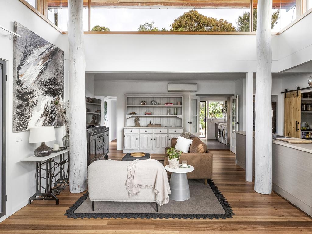 Light from the second level flows through to the living room below with tree-trunk like white posts in the centre.