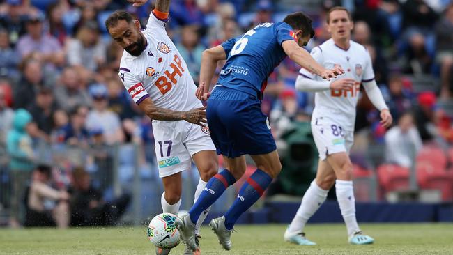 Steven Ugarkovic of the Newcastle Jets, centre, contests the ball against Diego Castro of Perth Glory during the round-5 A-League match with Glory. Picture: Getty Images