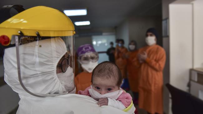 Staff applaud as a masked nurse carries baby Amine Tepe, who was diagnosed with COVID-19 when she was 37 days old, as she is taken out of the intensive care unit at an Istanbul hospital this week. Picture: AP