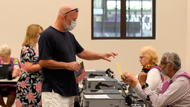 Voters wearing masks receive their ballots at Brisbane City Hall in Brisbane on Saturday.