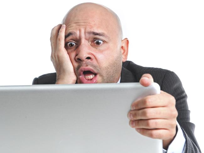 businessman in crisis and stress at computer laptop holding monitor watching online finances drop down or loosing money internet gambling isolated on white background