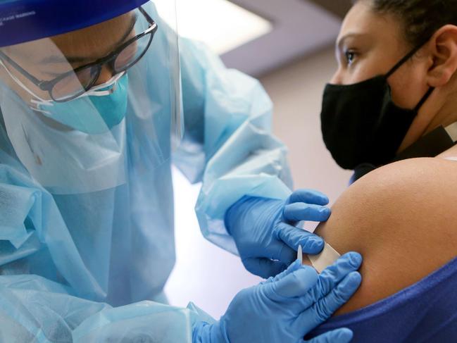 LAKEWOOD, CALIFORNIA - OCTOBER 14: A nurse applies a band- aid after administering the flu vaccination shot to a woman at a free clinic held at a local library on October 14, 2020 in Lakewood, California. Medical experts are hoping the flu shot this year will help prevent a âtwindemicâ- an epidemic of influenza paired with a second wave of COVID-19 which could lead to overwhelmed hospitals amid the coronavirus pandemic.   Mario Tama/Getty Images/AFP == FOR NEWSPAPERS, INTERNET, TELCOS & TELEVISION USE ONLY ==