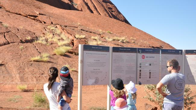 Tourists contemplate a plea by the Anangu people to stay off Uluru. Photo: Zach Hope