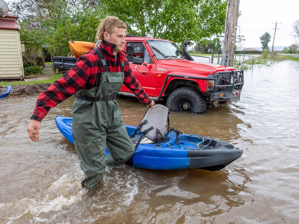 Riley Davis uses a kayak to cross the floodwaters. Picture: Jason Edwards