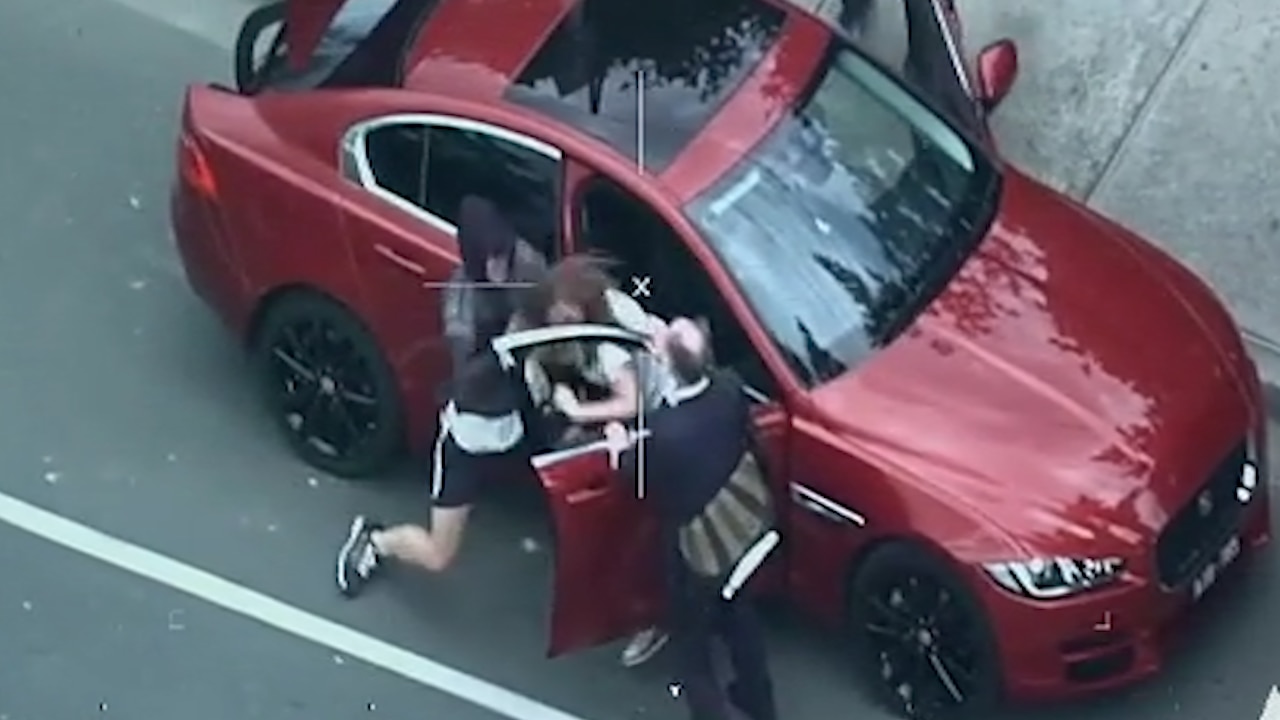 Police helicopter footage shows the moment a car thief pulls a woman out of her car.