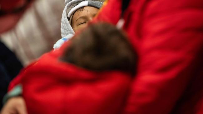 A boy sleeps in his mothers arms during an Amica Center for Immigrant Rights (formerly known as CAIR Coalition) presentation on immigration enforcement at a school in Washington, DC on January 10, 2025. In preparation for increased immigration enforcement, a DC school hosted a "know your rights" presentation given by Amica Center attorney, Atenas Burrola Estrada. Organized by concerned parents and open to members of the school and the community at large, attendees learned about their rights  in regards to Immigration Customs and Enforcement (ICE) raids and investigations that might effect themselves, their families, and their communities. (Photo by ANDREW CABALLERO-REYNOLDS / AFP)