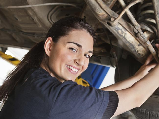 Portrait of smiling young female mechanic inspecting a CV joing on a car in auto repair shop. Free to use from iStock