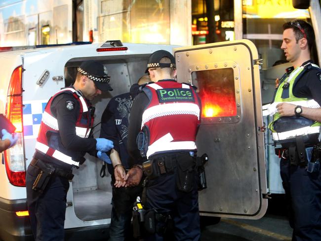 A man is loaded into the back of a divisional man after being arrested near McDonalds in Swanston St. Picture Yuri Kouzmin