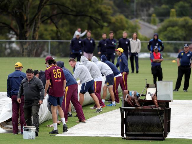 Players help remove the covers during a rain delay. Picture: Mark Dadswell/AAP