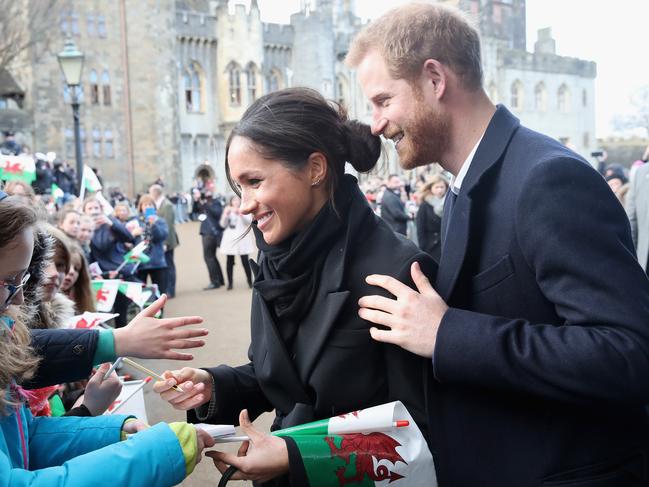 Meghan Markle writes a note for 10 year old Caitlin Clarke from Marlborough Primary School as Prince Harry looks on during a walkabout at Cardiff Castle on January 18, 2018 in Cardiff, Wales. Picture: Getty