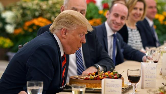 Donald Trump blows out a candle after being presented a cake during a working lunch with Singapore's Prime Minister Lee Hsien Loong yesterday. Picture: Ministry of Communications and Information of Singapore/AFP