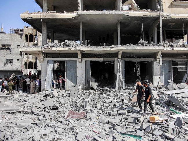 Men walk through rubble following Israeli bombardment on the four-storey Muqat family house in the Zarqa neighbourhood in the north of Gaza City on October 26, 2024 amid the ongoing war in the Palestinian territory between Israel and Hamas. (Photo by Omar AL-QATTAA / AFP)