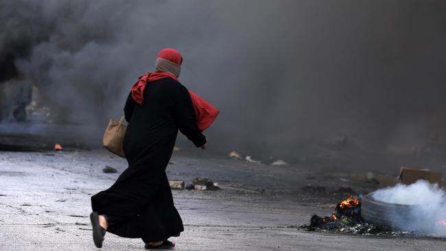 A woman runs to safety during clashes between Palestinians and Israeli forces at the northern entrance of the West Bank city of Ramallah on Friday. Picture: Zain Jaafar/AFP