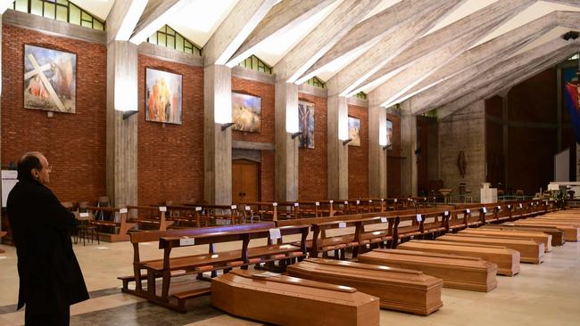 A priest stands by coffins kept in a church near Bergamo, Lombardy, on March 26, 2020, during the country's first deadly wave of Covid-19. Picture: AFP