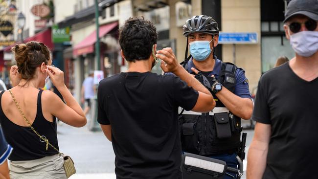 A Paris municipal police officer asks people to put on their masks in Paris. Picture: AFP.