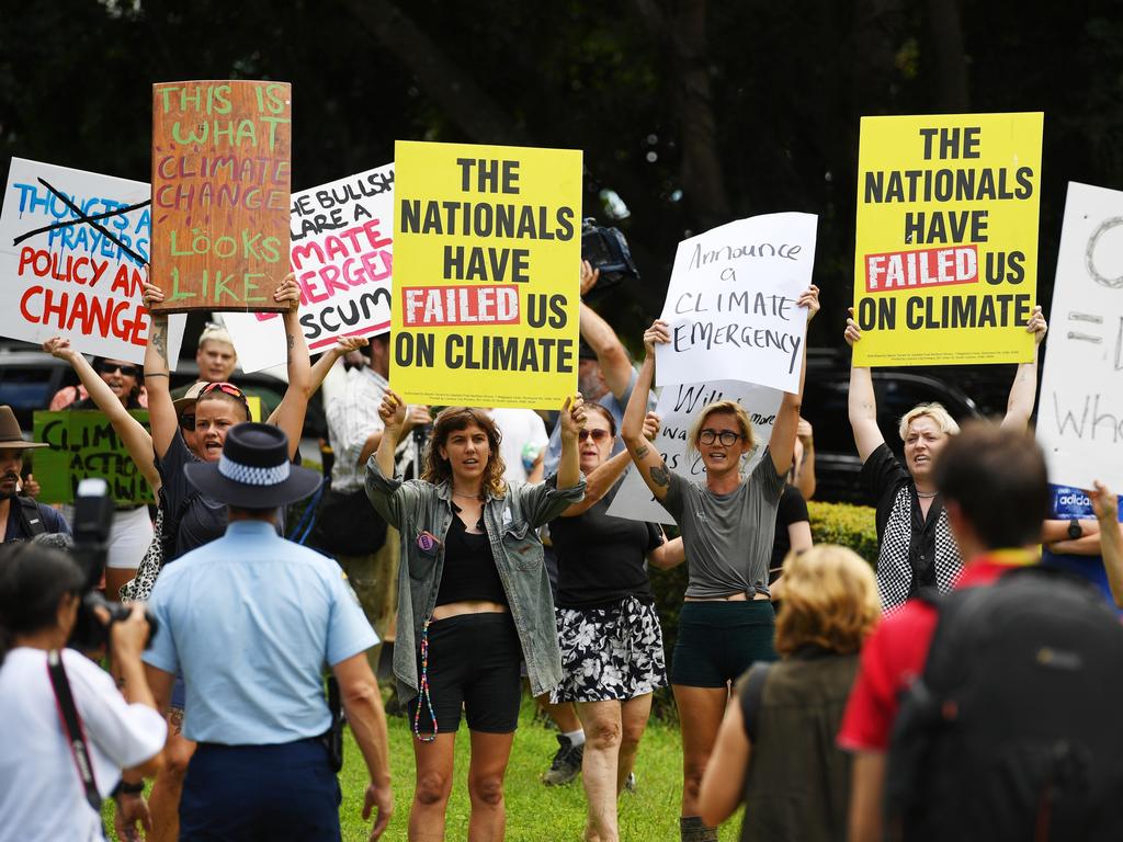 As the Prime Minister announced further funding for flood victims, protesters waited outside carrying signs demanding immediate climate action. Picture: Elise Derwin / NewsCorp