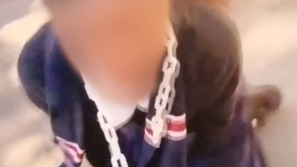 A laughing girl in a Brisbane State High School uniform with a chain around her neck, being dragged along like a dog by a male peer.