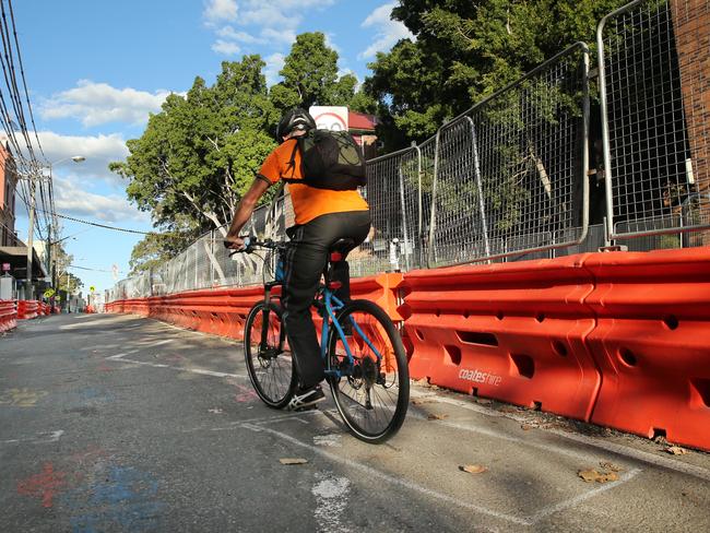 A cyclist makes his way up ruptured Devonshire St in Surry Hills, where bollards are part of the furniture. Picture: Richard Dobson