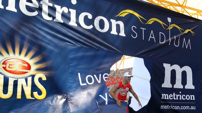 Gary Ablett busts through a banner at the launch of Metricon Stadium in 2011. Picture: Adam Head