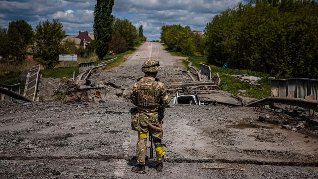 A soldier of the Kraken Ukrainian special forces unit observes the area at a destroyed bridge on the road near the village of Rus'ka Lozova, north of Kharkiv, in May. Picture: AFP