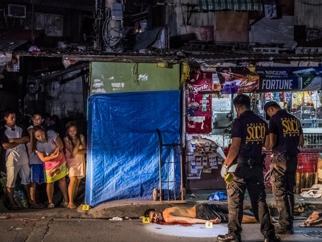 Police with the body of Michael Araja, 29, who neighbours said was killed by two men riding by on a motorbike, in the Pasay district of Manila. Picture: Daniel Berehulak/The New York Times/Redux/Headpress