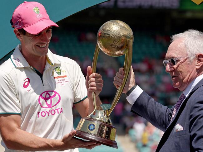 Australia’scaptain Pat Cummins (L) is handed the trophy by former Australian cricketer Allan Border. Picture: AFP