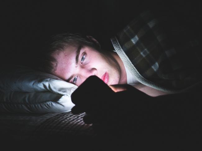 Generic image of child in bed with mobile phone