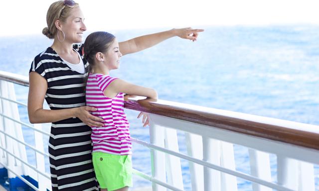 A mother points out across the horizon to her cute daughter. The two are enjoying a family cruise ship vacation together
