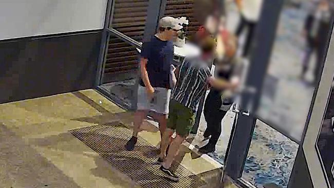 A security guard on the inside of the pub talks to two men after a brutal fight at the Windaroo Tavern last week, when a motorcycle was stolen.