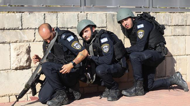 Members of the Israeli forces take cover on the side of a street in Ashkelon as sirens wail while barrages of rockets are fired from the Gaza Strip into Israel.