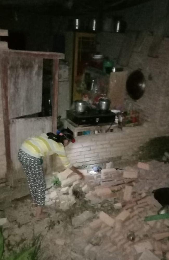 A resident is seen beside the collapsed brick wall of her house at Tobadak village in Central Mamuju, western Sulawesi province. Picture: AFP