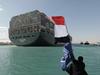 A picture released by Egypt's Suez Canal Authority on March 29, 2021, shows a man waving the Egyptian flag after Panama-flagged MV 'Ever Given' container ship was fully dislodged from the banks of the Suez. - The ship was refloated and the Suez Canal reopened, sparking relief almost a week after the huge container ship got stuck and blocked a major artery for global trade. Salvage crews have been working around the clock ever since the accident which has been blamed on high winds and poor visibility during a sandstorm. (Photo by - / SUEZ CANAL AUTHORITY / AFP)