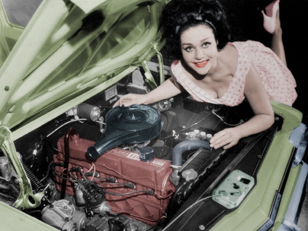 A model leaning over the ‘Red Engine’ of the Holden EH motor car.