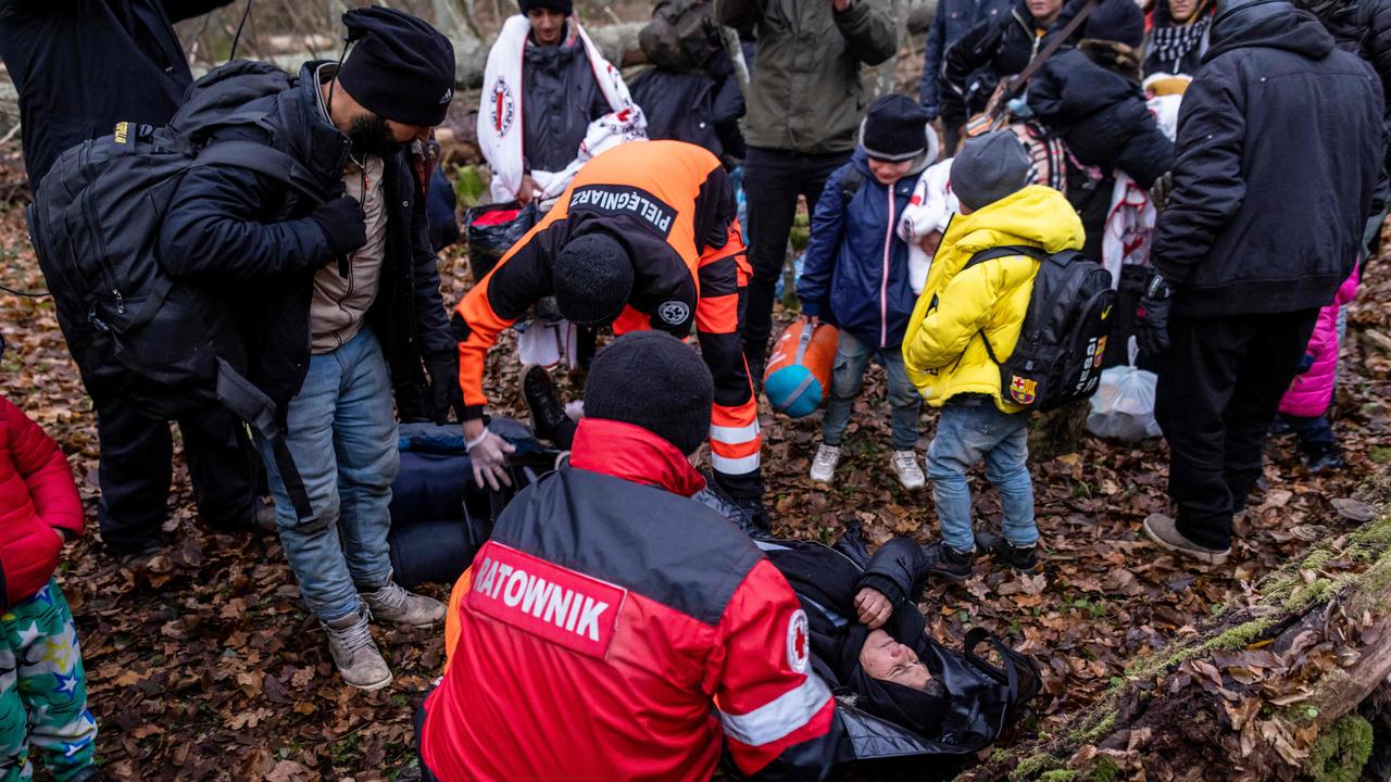 Paramedics prepare to transport an elderly woman as the border guard patrol prepares to take the family to the town of Narewka, Poland. Picture: Wojtek Radwanski/AFP