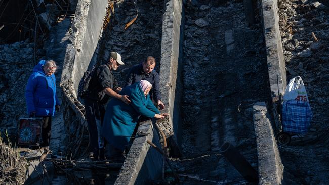 An elderly lady is helped across a destroyed bridge in Bakhmut, Donetsk. Picture: Getty Images