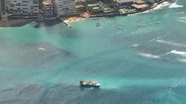 In this photo provided by the U.S. Coast Guard, a fishing vessel sits grounded on a reef off the shore of Honolulu, Wednesday, Oct. 11, 2017. The U.S. Coast Guard rescued over a dozen foreign fishermen and their American captain from the 79-foot (24-meter) U.S.-flagged commercial fishing vessel that ran aground off the shore of Waikiki on Tuesday night. (John Manganaro/U.S. Coast Guard via AP)