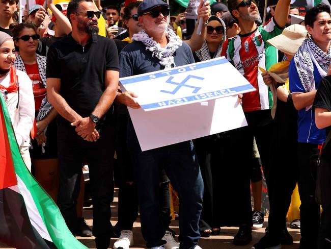 SYDNEY, AUSTRALIA - NewsWire Photos OCTOBER 6, 2024: A protester pictured holding  a flag that has a Nazi like symbol on it at the protest in Hyde Park. Protestors gather at Hyde Park in Sydney's CBD to demand an end to the ongoing war and Israel's current occupation of Gaza, and the escalating Israel-Lebanon conflict.Picture: NewsWire / Damian ShawAl Yazbek